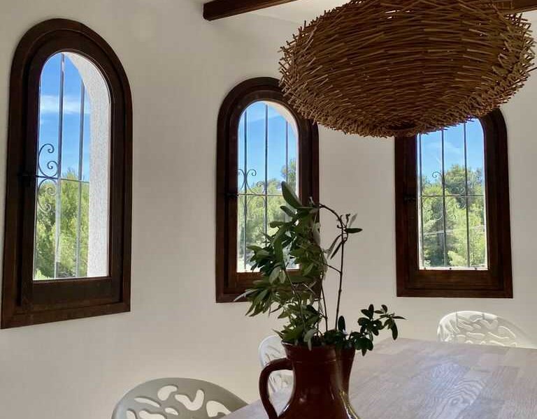 Deze villa in Benissa heeft een gezellige eetkamer met veel raampjes die op het groen uitkijken